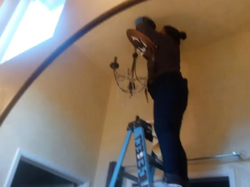 Electrician installing a chandelier in a Olyphant residence